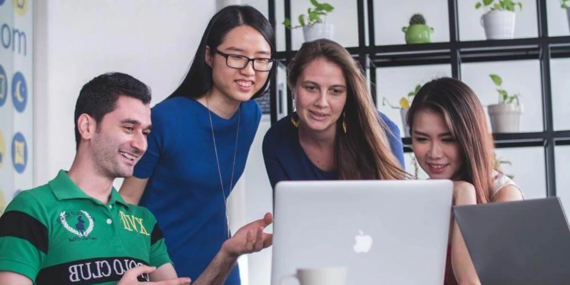 A group of students discussion in front of a laptop